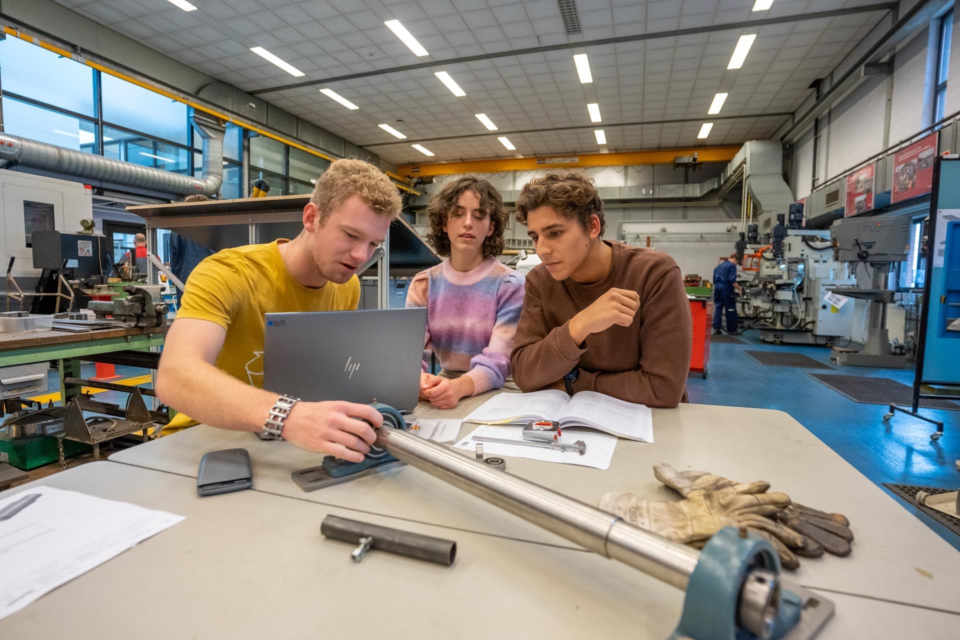 3 studenten van werktuigbouwkunde zitten in de werktruimte met bouwkundige tools