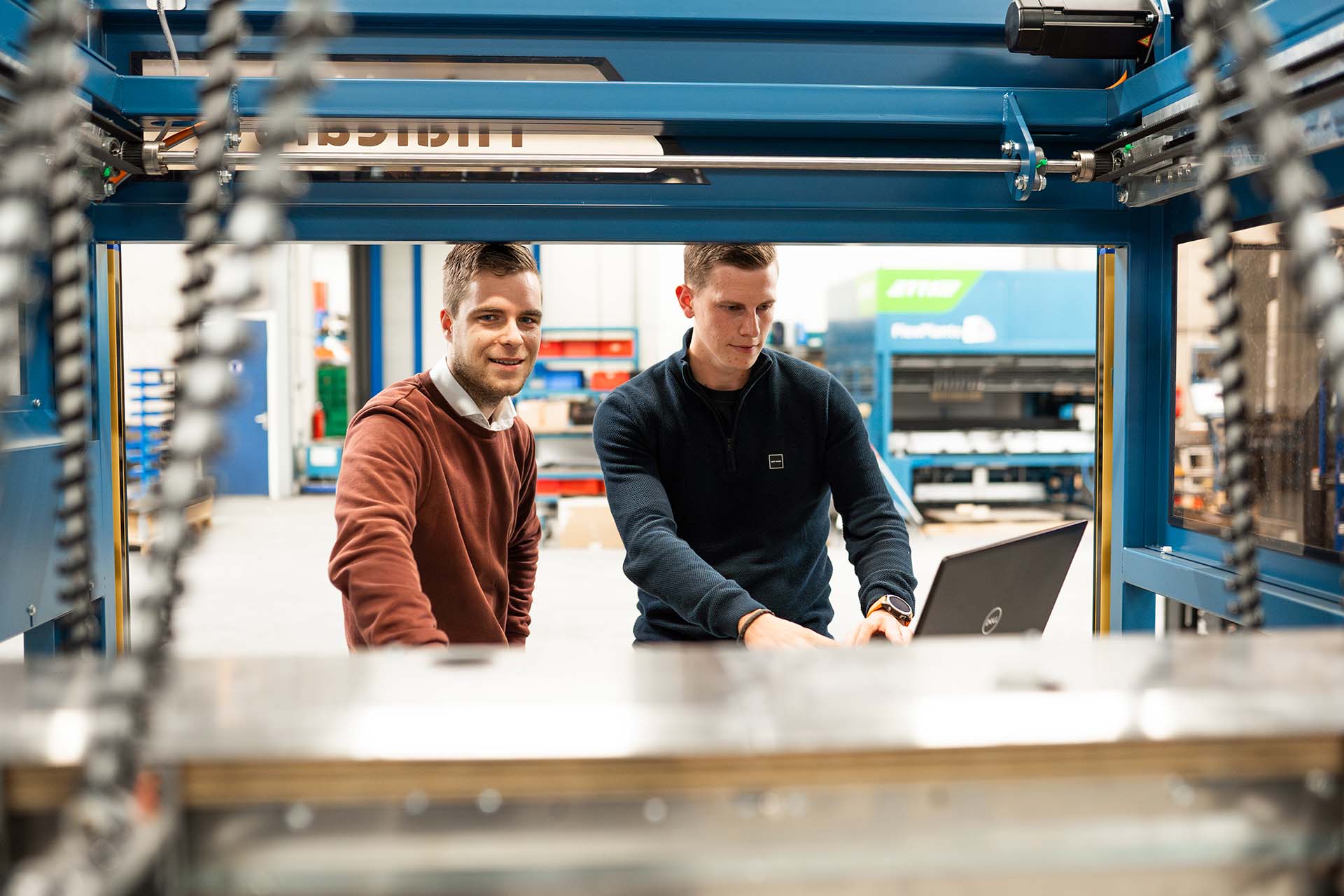 2 mechatronica deeltijdstudenten staan met hun laptop bij een machine