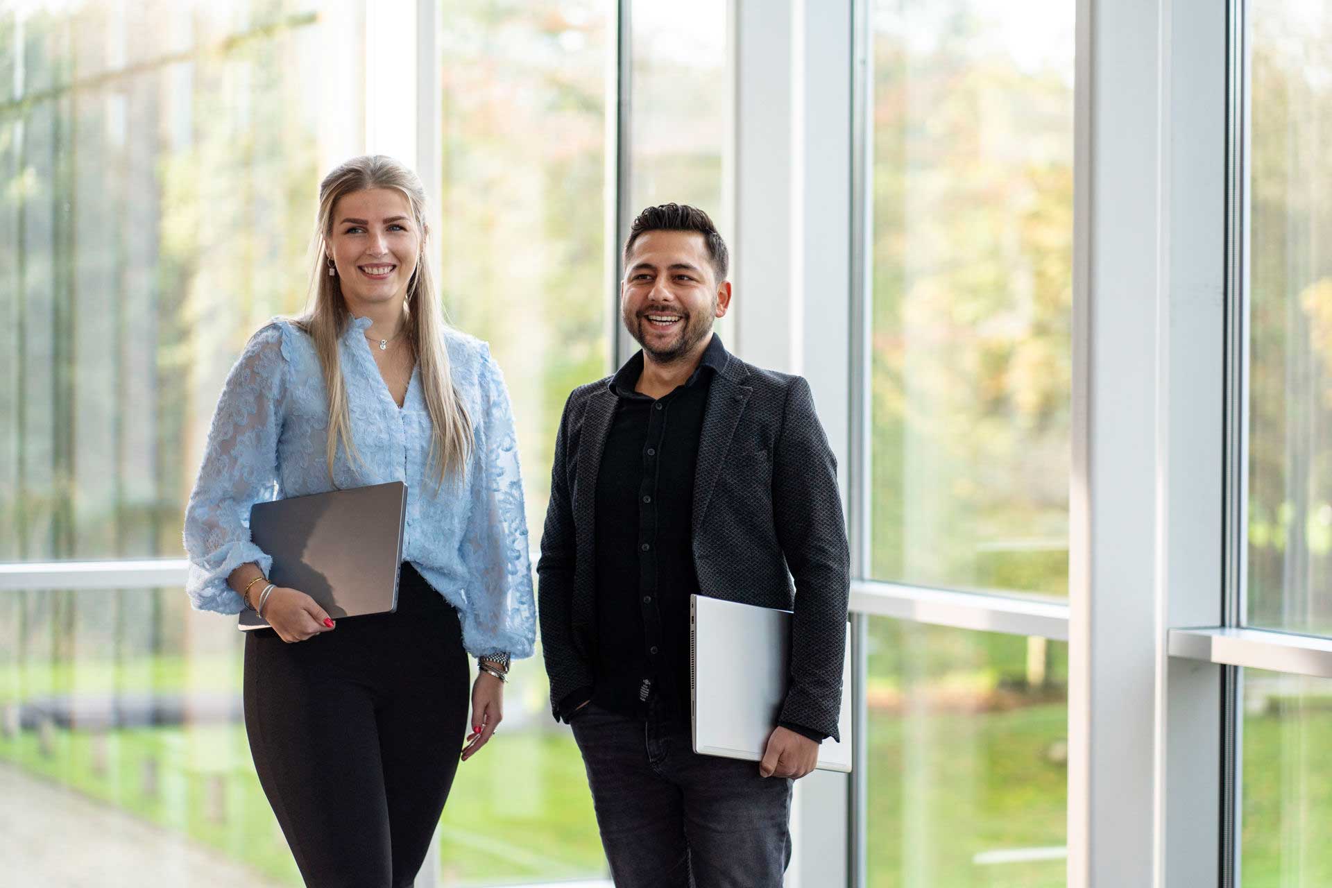 2 studenten van de master AI-translator staan met hun laptop in de hand