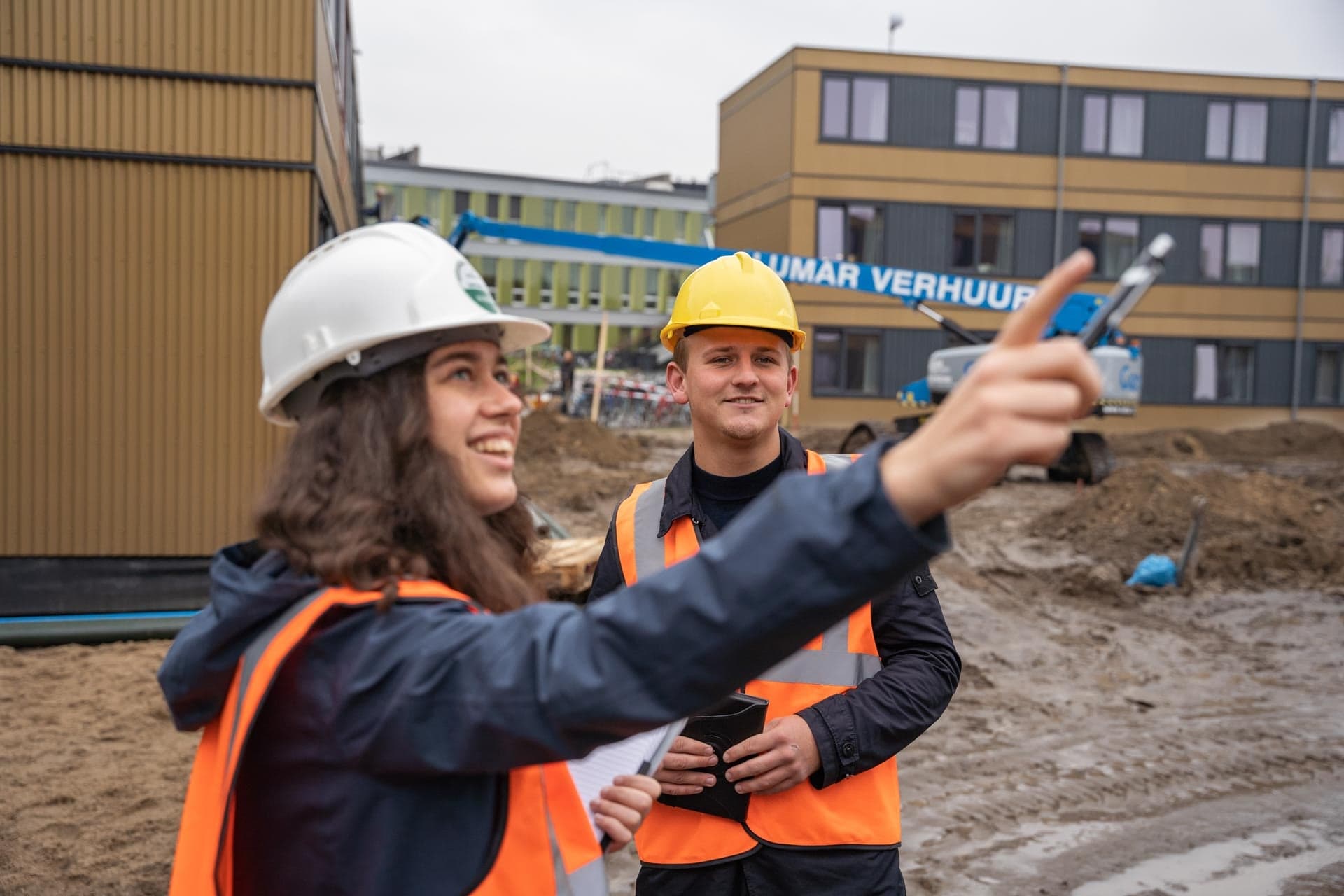 2 studenten van Bouwtechnische Bedrijfskunde staan op een bouwterrein