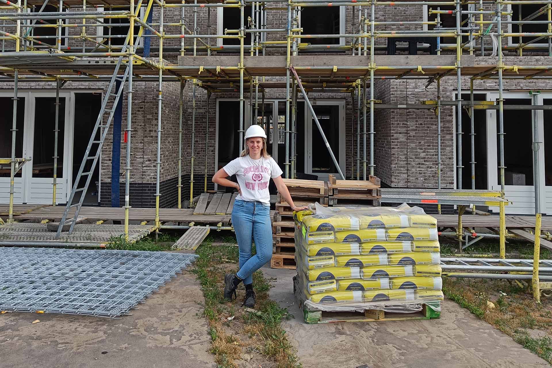 Student bouwtechnische bedrijfskunde staat voor een nieuwbouwwoning die in aanbouw is