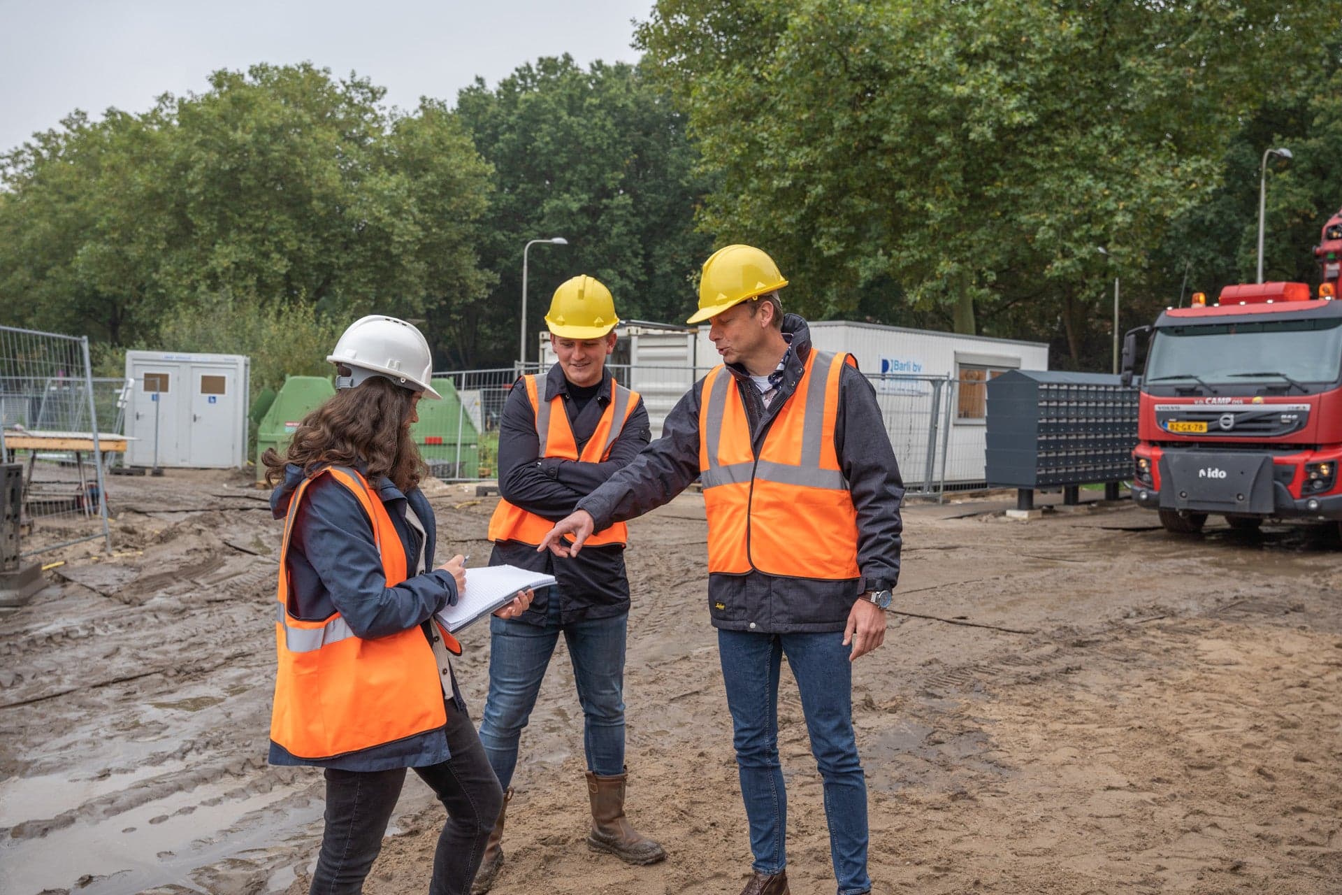 2 studenten van Bouwtechnische Bedrijfskunde staan samen met de projectleider op het bouwterrein