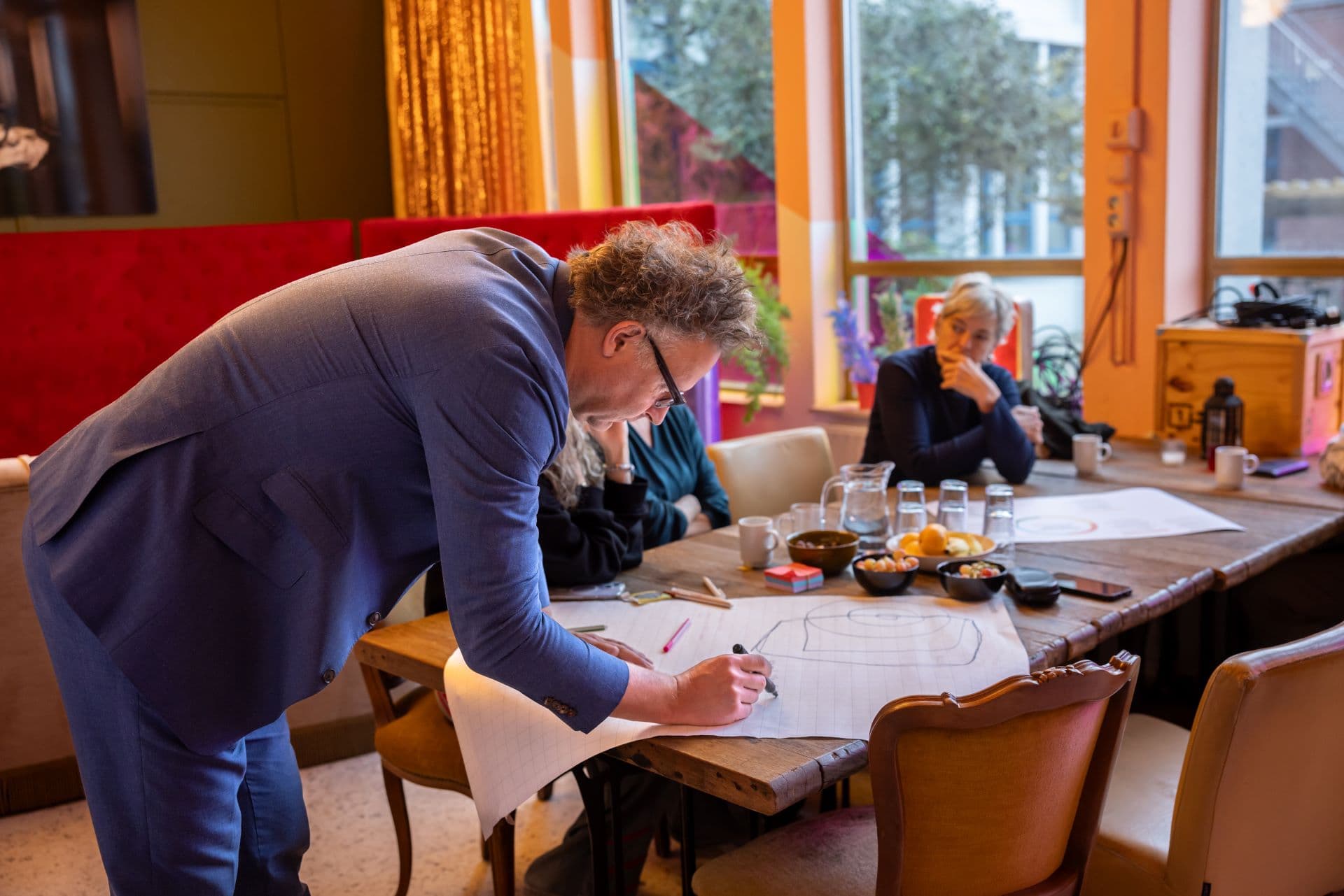 Lector Sebastian Olma van lectoraat Cultural and Creative Industries tekent iets op een flipover.
