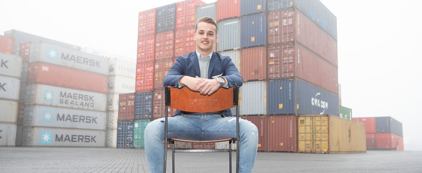 Arjan poseert op stoel voor stapel containers