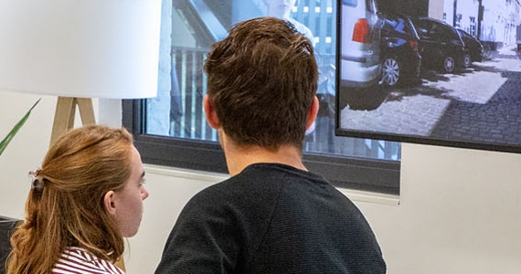 studente op hometrainer gekoppeld aan scherm, docent geeft uitleg
