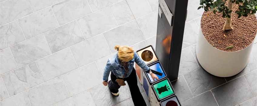 student loopt langs afvalbakken voor gescheiden afval