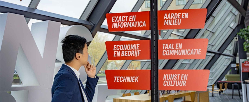 student staat voor een wegwijzer in een avans gebouw